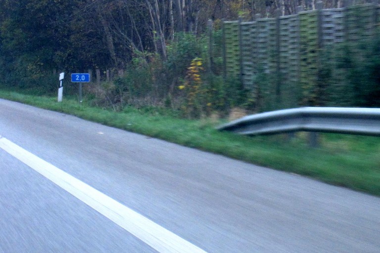 Blaues Schild am Fahrbahnrand der Autobahn
